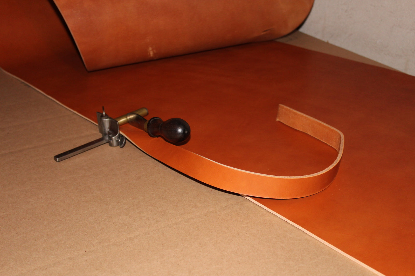 Leather hide being cut into straps with an antique plough gauge tool